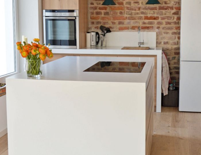 Arbeitsflächen in weißem Corian mit integriertem Spülbecken und bündig eingelassenem Kochfeld