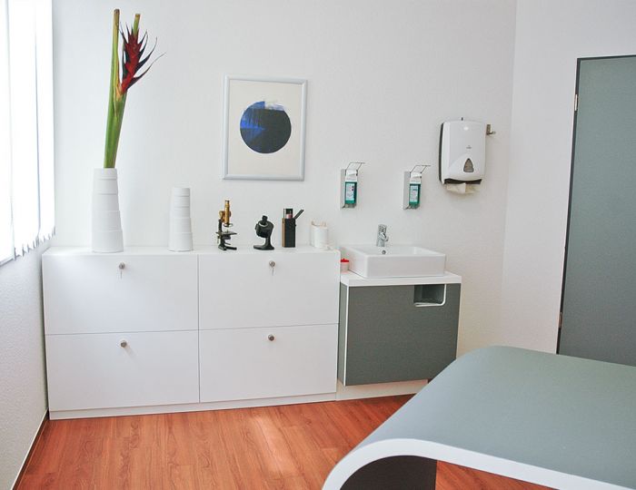 Behandlungszimmer mit Schrank, Tisch und Sideboard